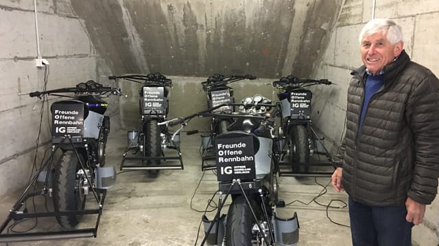 Ein älterer Mann steht vor schwarzen Motorrädern. Ein älterer Mann steht vor schwarzen Motorrädern.