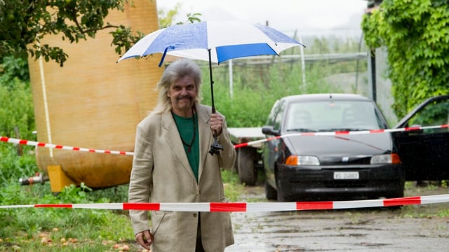 Mann mit Regenschirm auf einem Bauernhof. Mann mit Regenschirm auf einem Bauernhof.