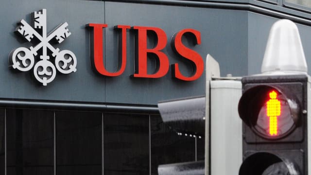 UBS-Logo davor eine Ampel auf rot. UBS-Logo davor eine Ampel auf rot.