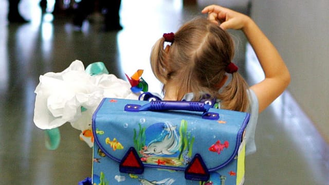 Schulmädchen mit Rucksack von hinten kratzt sich am Kopf Schulmädchen mit Rucksack von hinten kratzt sich am Kopf