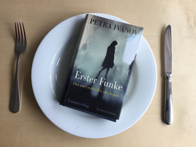 Das Buch «Erster Funke» von Petra Ivanov auf weissem Teller serviert mit Besteck Das Buch «Erster Funke» von Petra Ivanov auf weissem Teller serviert mit Besteck