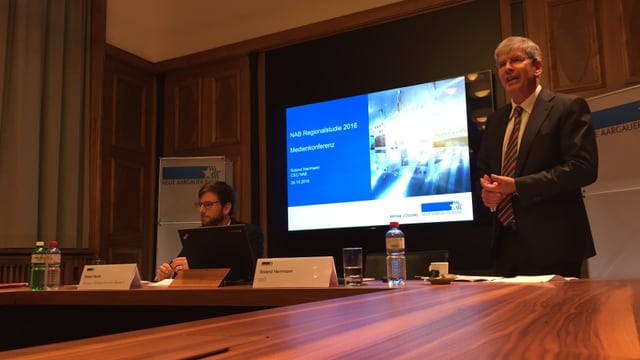 Medienkonferenz im Gebäude der Neuen Aargauer Bank in Aarau, im Hintergrund läuft eine Powerpoint-Präsentation. Medienkonferenz im Gebäude der Neuen Aargauer Bank in Aarau, im Hintergrund läuft eine Powerpoint-Präsentation.