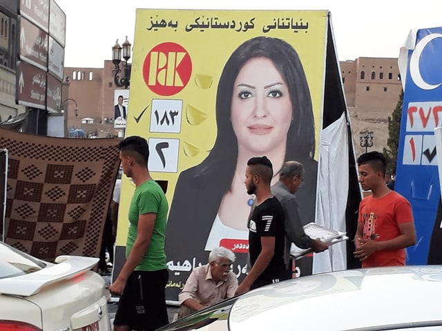 Männer gehen an Wahlplakat vorbei Männer gehen an Wahlplakat vorbei