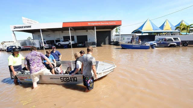 Menschen steigen in ein Boot, dahinter eine Tankstelle. Menschen steigen in ein Boot, dahinter eine Tankstelle.