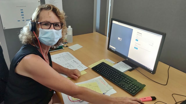 Eine Frau mit Mundschutz vor einem Computer. Eine Frau mit Mundschutz vor einem Computer.