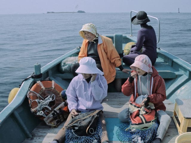 Vier Frauen sitzen auf einem Fischerboot. Vier Frauen sitzen auf einem Fischerboot.