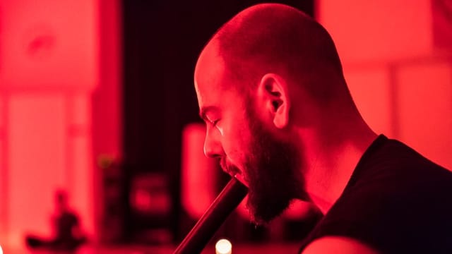 Mann mit geschlossenen Augen spielt ein nicht genau erkennbares Instrument. Mann mit geschlossenen Augen spielt ein nicht genau erkennbares Instrument.