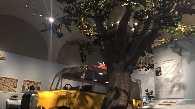Ein grosser Baum und eine gelbes Postauto in einem Museum Ein grosser Baum und eine gelbes Postauto in einem Museum