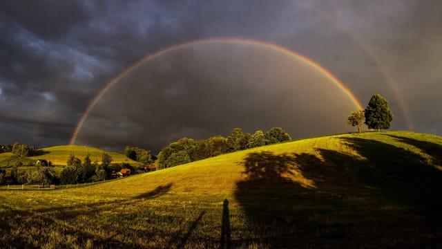 Toller Doppelter Regenbogen über saftigen Wiesen.