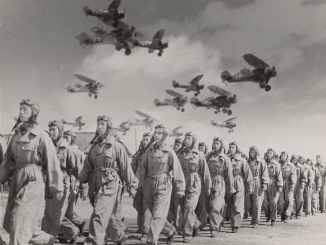 Piloten gehen in einer Reihe. Darüber sind verschwommene Flugzeuge zu sehen. Piloten gehen in einer Reihe. Darüber sind verschwommene Flugzeuge zu sehen.