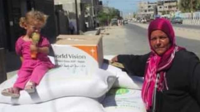 Ein Mädchen sitzt auf weissen Lebensmittelsäcken vor einer Schachtel mit dem World-Vision-Logo, daneben steht eine Frau mit Kopftuch. Ein Mädchen sitzt auf weissen Lebensmittelsäcken vor einer Schachtel mit dem World-Vision-Logo, daneben steht eine Frau mit Kopftuch.