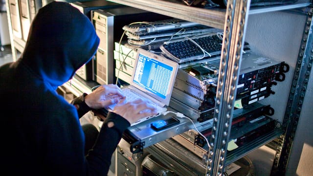 An Mann gibt Befehle in einen an andere Recher angeschlossenen Laptop ein. An Mann gibt Befehle in einen an andere Recher angeschlossenen Laptop ein.