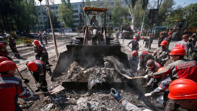 Arbeiter räumen mit Hilfe von Baumaschinen Barrikaden weg. Arbeiter räumen mit Hilfe von Baumaschinen Barrikaden weg.