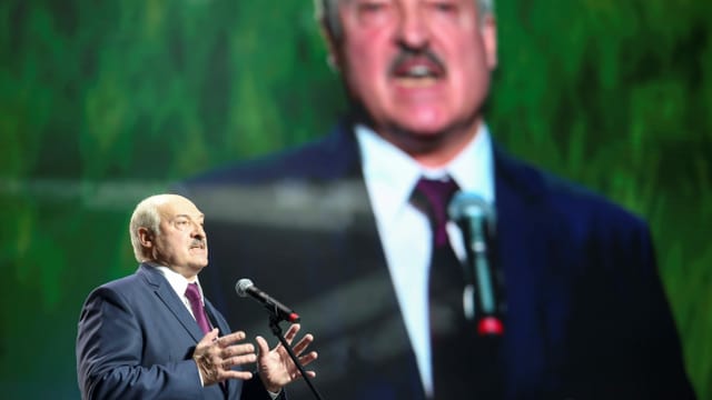 Lukaschenko spricht in ein Mikrofon, hinter ihm ist eine grosse Projektion von ihm zu sehen. Lukaschenko spricht in ein Mikrofon, hinter ihm ist eine grosse Projektion von ihm zu sehen.