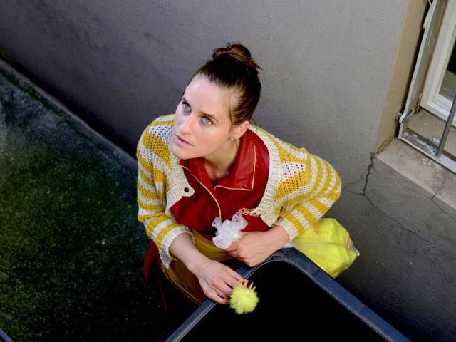 Johanna Bantzer als Lily mit einer Tüte Recyclingmaterial vor einer Tonne. Johanna Bantzer als Lily mit einer Tüte Recyclingmaterial vor einer Tonne.