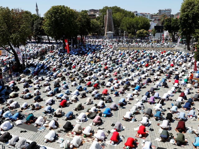 Hunderte Gläubige beten draussen auf Teppichen.