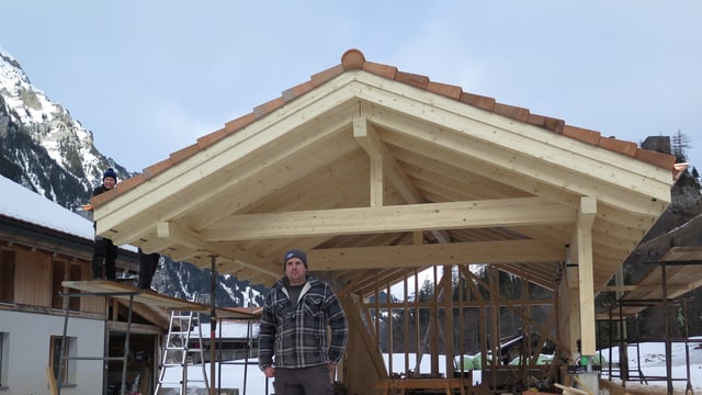 Mann vor Holzhaus im Bau Mann vor Holzhaus im Bau