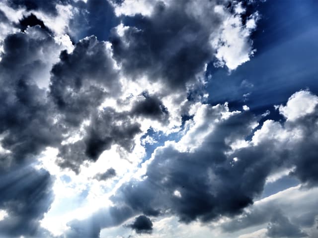 Dunkle, aber kleine Wolken, dazwischen Sonnenstrahlen.