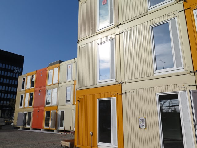 Eine Containersiedlung - mit orangen und beigen Containern. Dahinter der blaube Himmel. Eine Containersiedlung - mit orangen und beigen Containern. Dahinter der blaube Himmel.