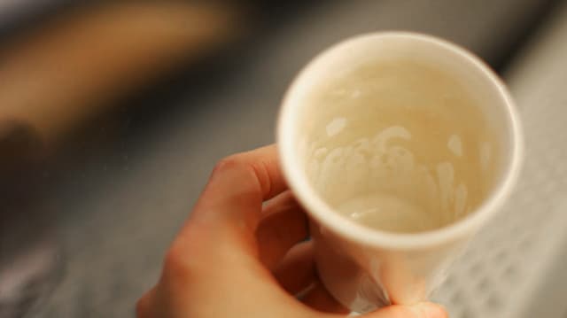 Eine Hand hält eine leere Kaffeetasse.