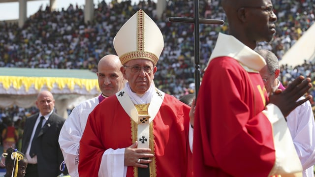 Papst Franziskus beim Einzug in ein Stadion. Zahlreiche Messeteilnehmer im Hintergrund