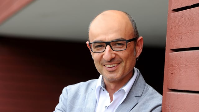 Aldo Magno lehnt sich an eine Hauswand. Aldo Magno lehnt sich an eine Hauswand.