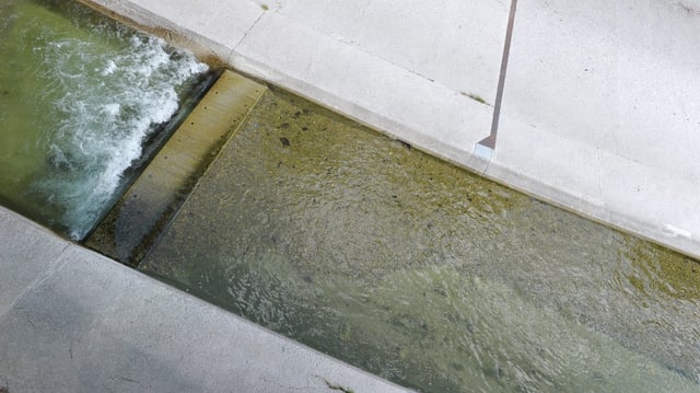 Ein kleiner Fluss fliesst durch einen Betonkanal. Ein kleiner Fluss fliesst durch einen Betonkanal.