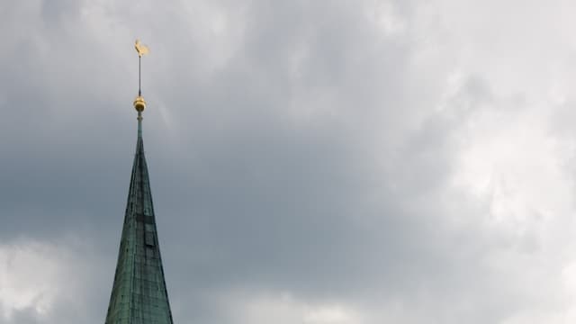 Kirchturmspitze vor bewölktem Himmel 
