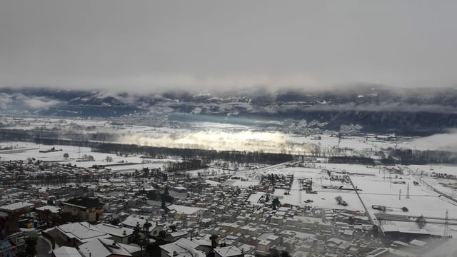 Blick auf die verschneite Magadinoebene mit einem einzigen sonnigen Fleck. Blick auf die verschneite Magadinoebene mit einem einzigen sonnigen Fleck.
