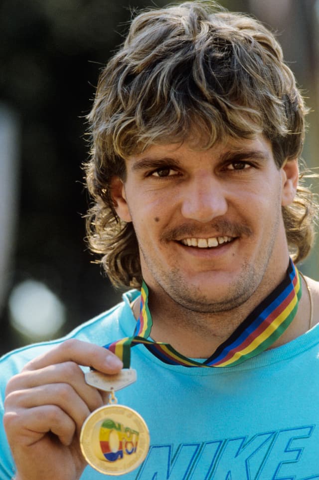 Werner Günthör streckt seine Goldmedaille, die um den Hals hängt, in die Kamera. Werner Günthör streckt seine Goldmedaille, die um den Hals hängt, in die Kamera.