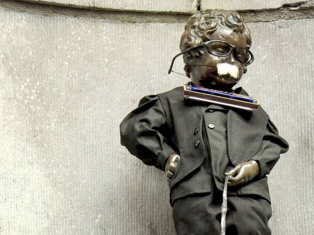 Der «Manneken Pis» in Brüssel wurde mit Bart und Mundharmonika bekelbt. Der «Manneken Pis» in Brüssel wurde mit Bart und Mundharmonika bekelbt.