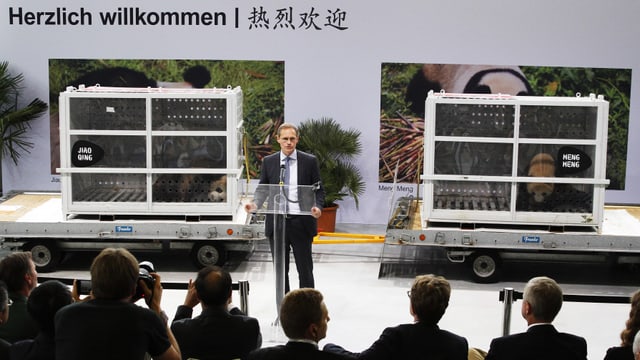 Müller spricht vor den Medien. Hinter ihm stehen die beiden Transportboxen, in denen die Pandas zu sehen sind. Müller spricht vor den Medien. Hinter ihm stehen die beiden Transportboxen, in denen die Pandas zu sehen sind.
