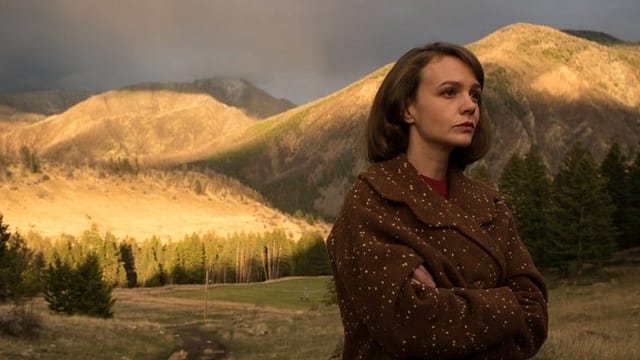 Eine Frau steht vor einer hügeligen Landschaft Eine Frau steht vor einer hügeligen Landschaft