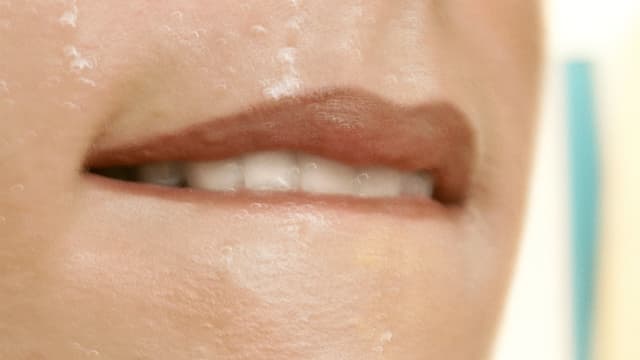 Eine Frau beisst sich mit den Zähnen auf ihre Unterlippe. Eine Frau beisst sich mit den Zähnen auf ihre Unterlippe.