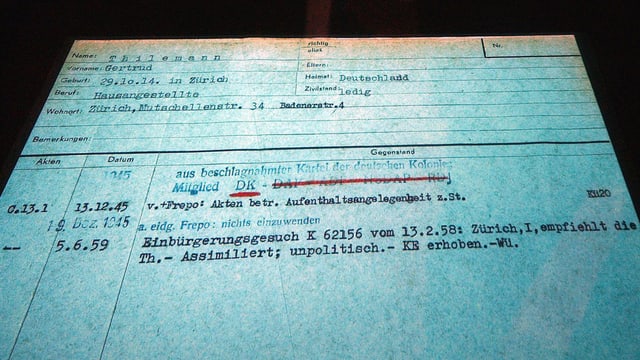 Ein grösseres Blatt mit Schreibmaschinenschrift betippt. Der Eintrag von 1945, wonach sie Mitglied der NSDAP sei, ist mit rotem Filzstift oder Kugelschreiber durchgestrichen. 