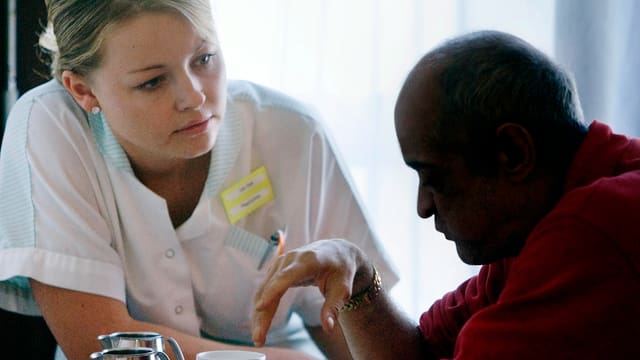Eine Pflegerin kümmert sich um einen Demenzkranken Eine Pflegerin kümmert sich um einen Demenzkranken