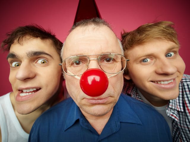 Drei Männer, einer mit roter Clownnase.