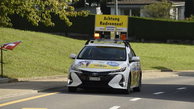 Auto mit einem Schild "Achtung Radrennen" Auto mit einem Schild "Achtung Radrennen"