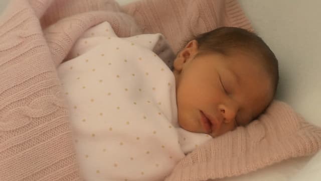 Ein Baby eingehüllt in eine rosa Wolldecke. Ein Baby eingehüllt in eine rosa Wolldecke.