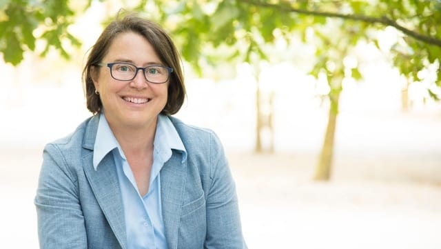 Frau mit pinker Bluse vor grüner Hecke Frau mit pinker Bluse vor grüner Hecke