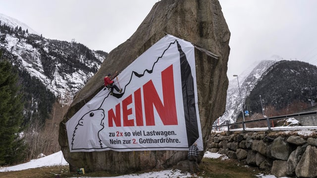 Ein Mann montiert ein Plakat gegen die zweite Gotthard-Röhre ab Ein Mann montiert ein Plakat gegen die zweite Gotthard-Röhre ab