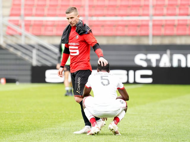 Fussballer streicht einem Gegner über den Kopf.