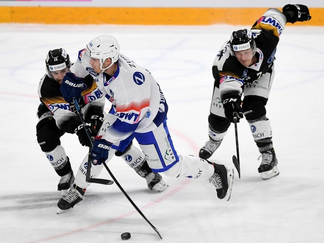 Lions-Spieler Pius Suter setzt sich gegen 2 Luganesi durch. Lions-Spieler Pius Suter setzt sich gegen 2 Luganesi durch.