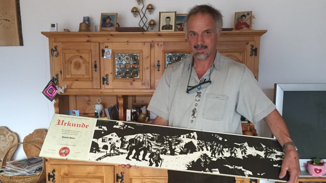 Il maletg mussa Jakob Dönz cun sia distincziun per merits spezials da l'Uniun grischuna da chatschadurs Il maletg mussa Jakob Dönz cun sia distincziun per merits spezials da l'Uniun grischuna da chatschadurs