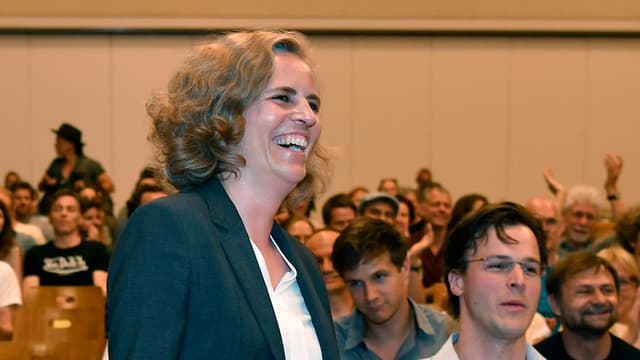 Eine Frau und ein Mann in einem Saal. Die Frau lacht, der Mann blickt ein bisschen unzufrieden. Eine Frau und ein Mann in einem Saal. Die Frau lacht, der Mann blickt ein bisschen unzufrieden.