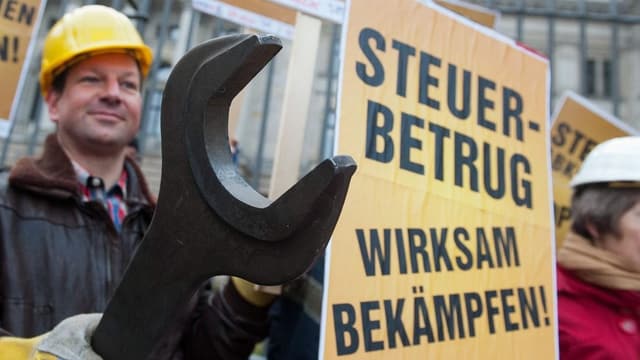 Demonstranten mit einem Plakat und einem grossen Werkzeug. Demonstranten mit einem Plakat und einem grossen Werkzeug.