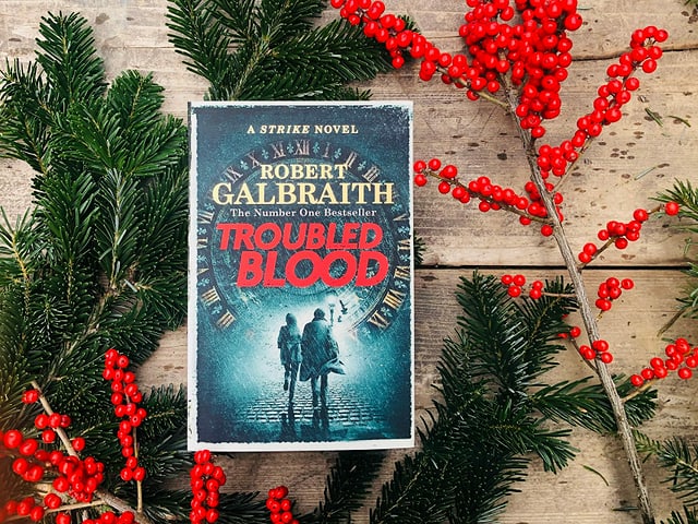 «Troubled Blood» von Robert Galbraith liegt auf Weihnachtsdekoration «Troubled Blood» von Robert Galbraith liegt auf Weihnachtsdekoration