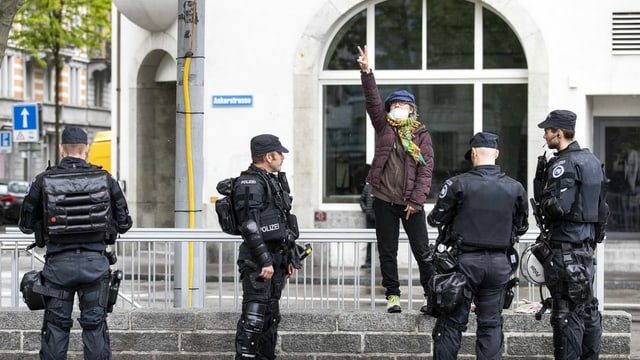 Frau mit Peacezeichen umzingelt von Stadtpolizisten in Zürich
