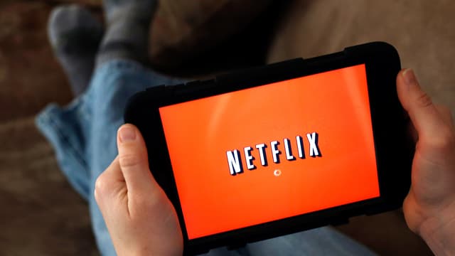 Zwei Hände halten ein Tablet, auf dessen Screen der Schriftzug «Netflix» zu lesen ist.