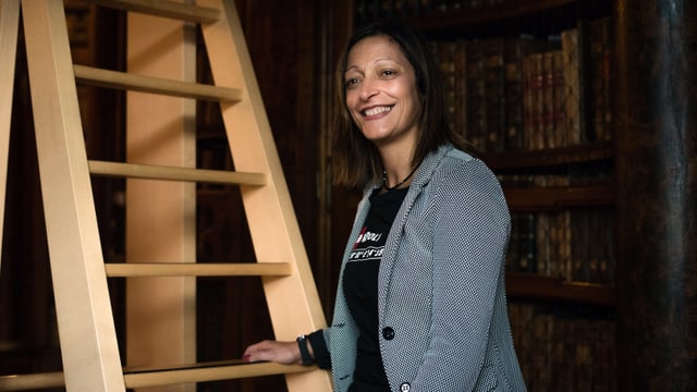 Eine Frau steht vor einer Leiter in einer Bibliothek Eine Frau steht vor einer Leiter in einer Bibliothek